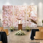Urnenaufbahrung vor einem dreiteiligen Roll-Up Display mit Kirschblüten in einer modernen Trauerhalle