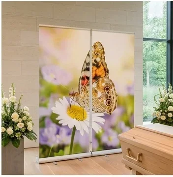 Helle moderne Trauerhalle mit Sarg, Blumenschmuck und Roll-Up Display mit Schmetterling und Margerite als würdevolle Dekoration