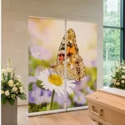 Helle moderne Trauerhalle mit Sarg, Blumenschmuck und Roll-Up Display mit Schmetterling und Margerite als würdevolle Dekoration