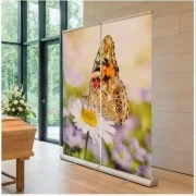 Roll-Up Display mit Schmetterling auf weißer Blüte in heller Trauerhalle neben einem Holzsarg