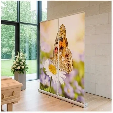 Holzsarg vor Roll-Up Display mit Schmetterlingsmotiv in moderner lichtdurchfluteter Trauerhalle