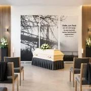 Roll-Up Display 3er-Set „Siehe, um Trost war mir sehr bange“ in einer modernen deutschen Trauerhalle mit hellem Sarg und dezentem Blumenschmuck - Infinity Abschiedsdesign