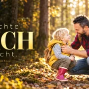 Sicherheit schenktEin Vater kniet vor seinem Sohn mit himbeerroten Gummistiefeln und sieht ihn ermutigend an; groß im Bild steht „Dich“.