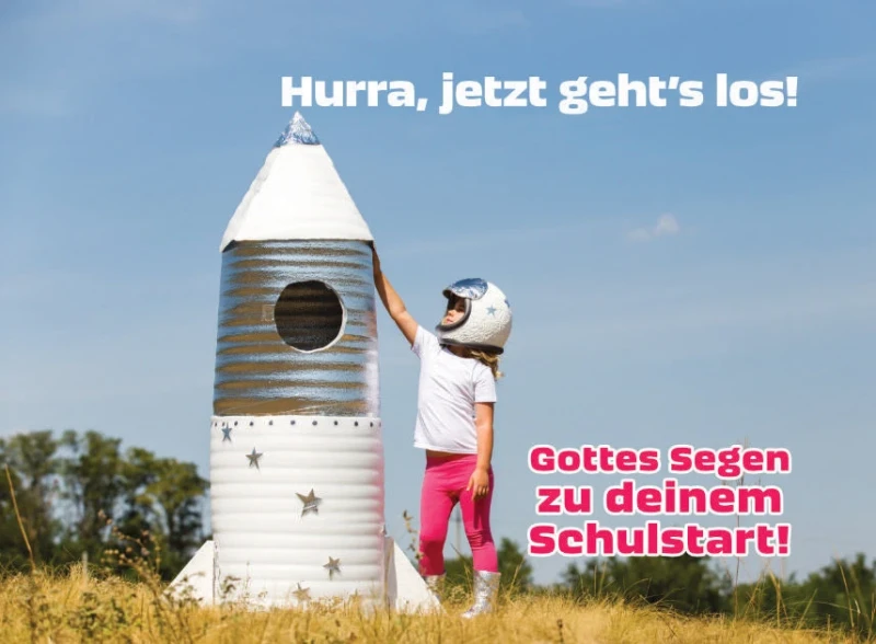 Kleines Mädchen als Astronautin auf einem Feld neben einer Papp-Rakete – Symbol für Aufbruch und Mut zum Schulanfang.