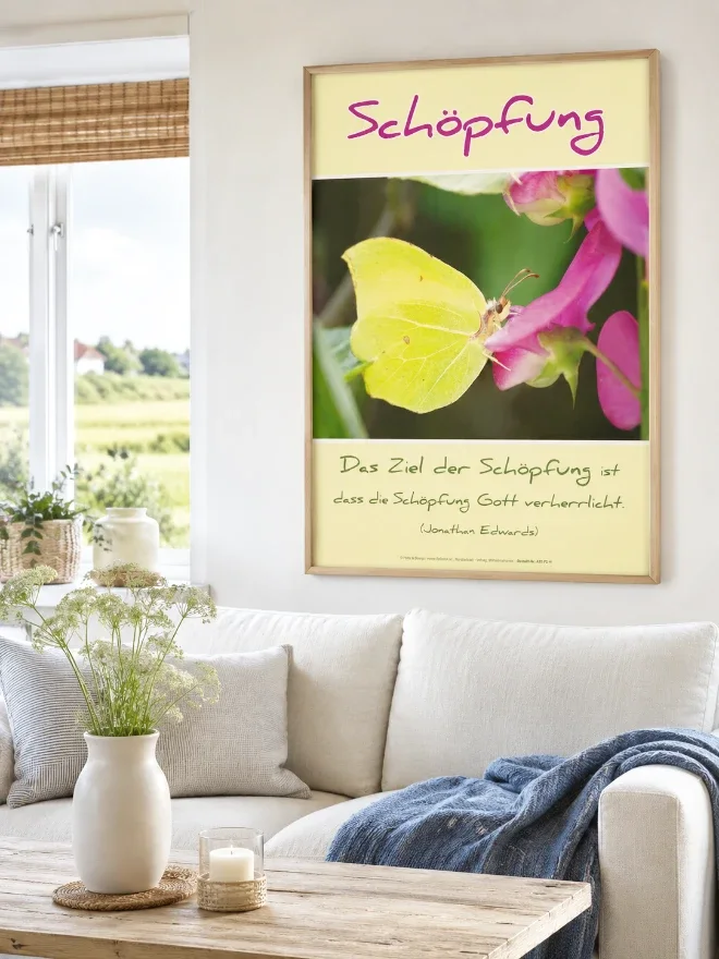 Hyperrealistische Wohnraumszene eines modernen friesischen Wohnzimmers mit heller, skandinavisch inspirierter Einrichtung und norddeutscher Wohnatmosphäre. Das christliche DIN-A2-Hochformat-Poster „Schöpfung“ mit einem Zitronenfalter auf einer rosafarbenen Blüte und dem inspirierenden Zitat von Jonathan Edwards hängt in einem hochwertigen Rahmen aus hellem Eichenholz über einem hellen Sofa. Natürliche Materialien, sanfte Farben und viel Tageslicht schaffen eine ruhige, einladende Atmosphäre und zeigen, wie stilvoll christliche Wanddekoration moderne Wohnräume bereichern kann.
