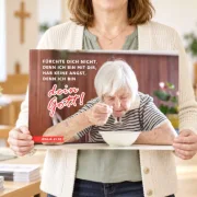 Gemeindemitarbeiterin hält ein DIN-A3-Poster zur Jahreslosung 2027 mit Jesaja 41,10 in den Händen