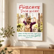 Leinwandbild zur Jahreslosung 2027 mit Vater-Sohn-Motiv über einer Holzkommode neben einer Vase im hellen Wohnzimmer.
