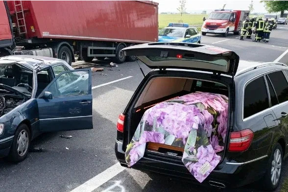 Bestatterbedarf beim Außeneinsatz nach Verkehrsunfall mit würdevoll abgedecktem Sarg im Bestattungsfahrzeug durch Infinity Sargbanner