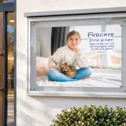 DIN-A1-Poster zur Jahreslosung 2027 mit Mädchen und Katze in einem Schaukasten am Gemeindehaus