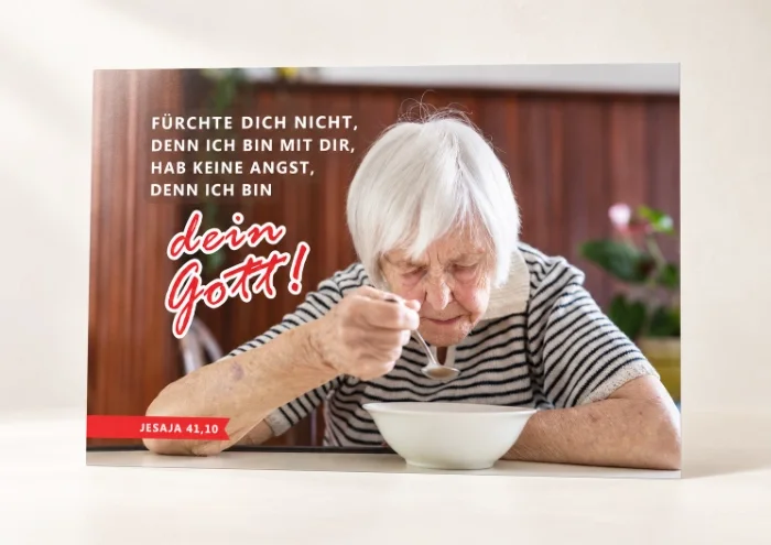 Poster Jahreslosung 2027 DIN A2 Du bist nicht allein – Betagte Seniorin am Tisch mit Bibelvers Jesaja 41,10