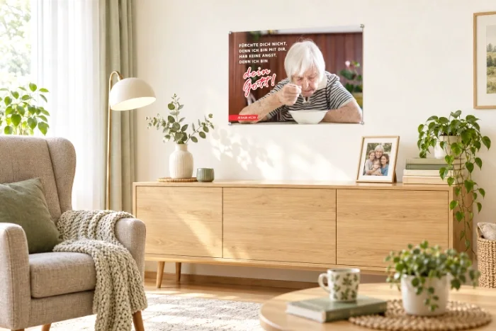 DIN-A2-Poster zur Jahreslosung 2027 im hellen Wohnzimmer einer älteren Person