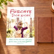 DIN-A4-Poster zur Jahreslosung 2027 mit Vater und Sohn im Wald auf einem Schreibtisch
