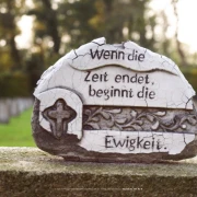 Keramische Figur auf verwittertem Grabstein aus der Nähe aufgenommen.