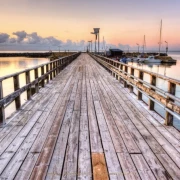 Holzsteg, der geradeaus in eine offene Landschaft führt.