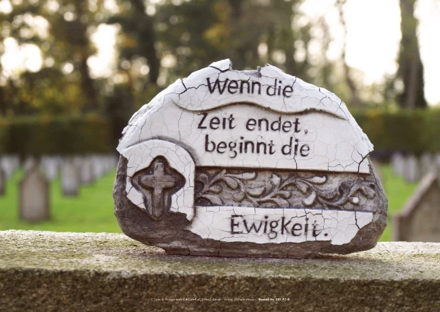 Gealterte Keramikfigur auf verwittertem Grabstein.