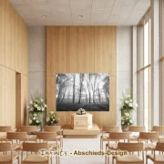 Schwarzweißes Wandbanner mit Waldmotiv über einem Sarg in heller Trauerhalle mit Stuhlreihen und Blumenarrangements
